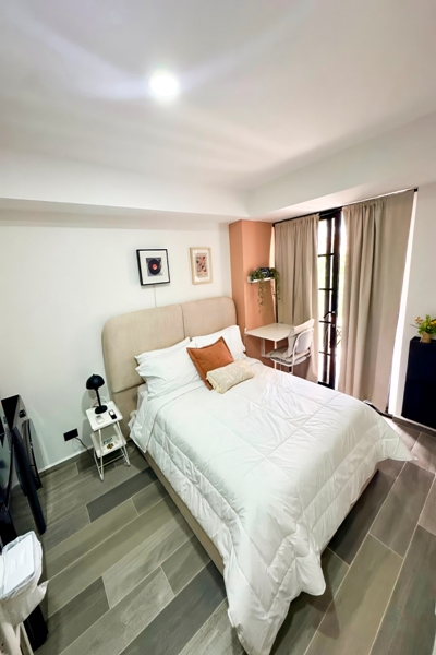 Dormitorio con cama vestida en blanco y acentos naranjas